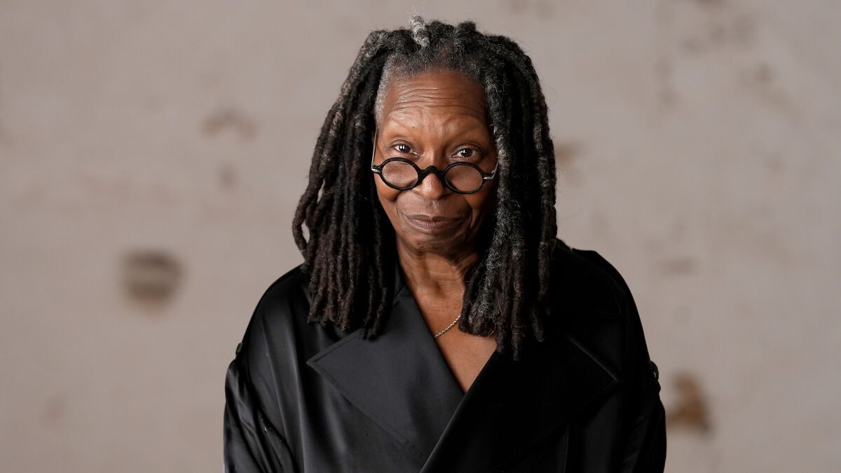 Whoopi Goldberg wearing glasses and a black coat, reacting furiously to a legal memo from The View producers.
