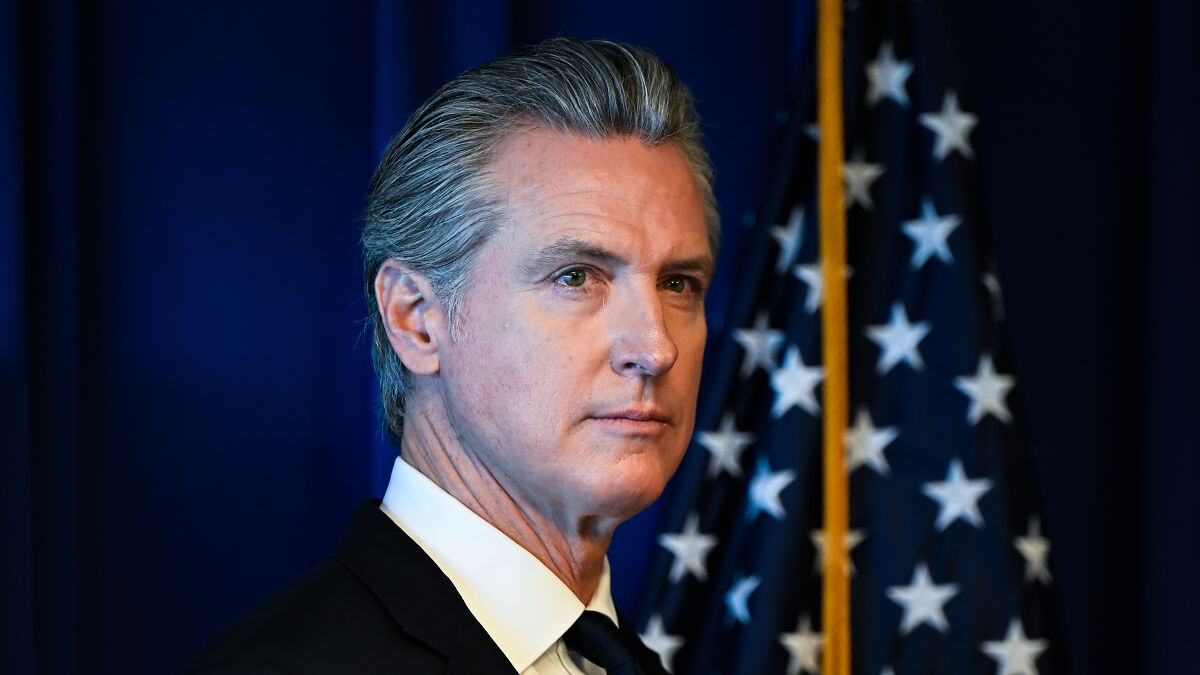 Gavin Newsom standing in front of an American flag during a speech after Proposition 50 election victory.
