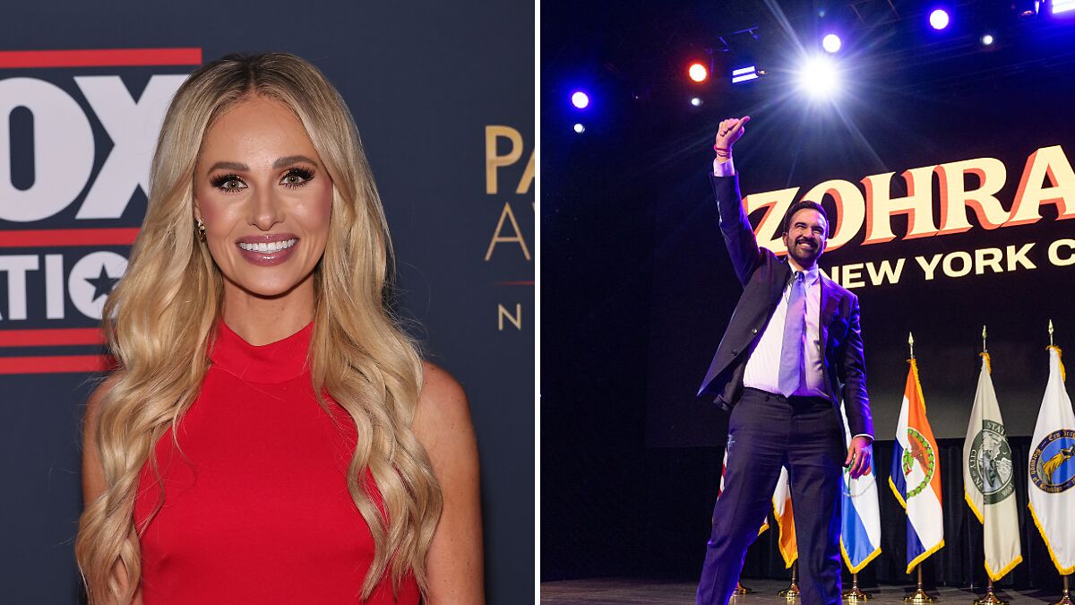 Tomi Lahren smiling at an event in red dress next to a man raising fist on stage under bright lights and flags.