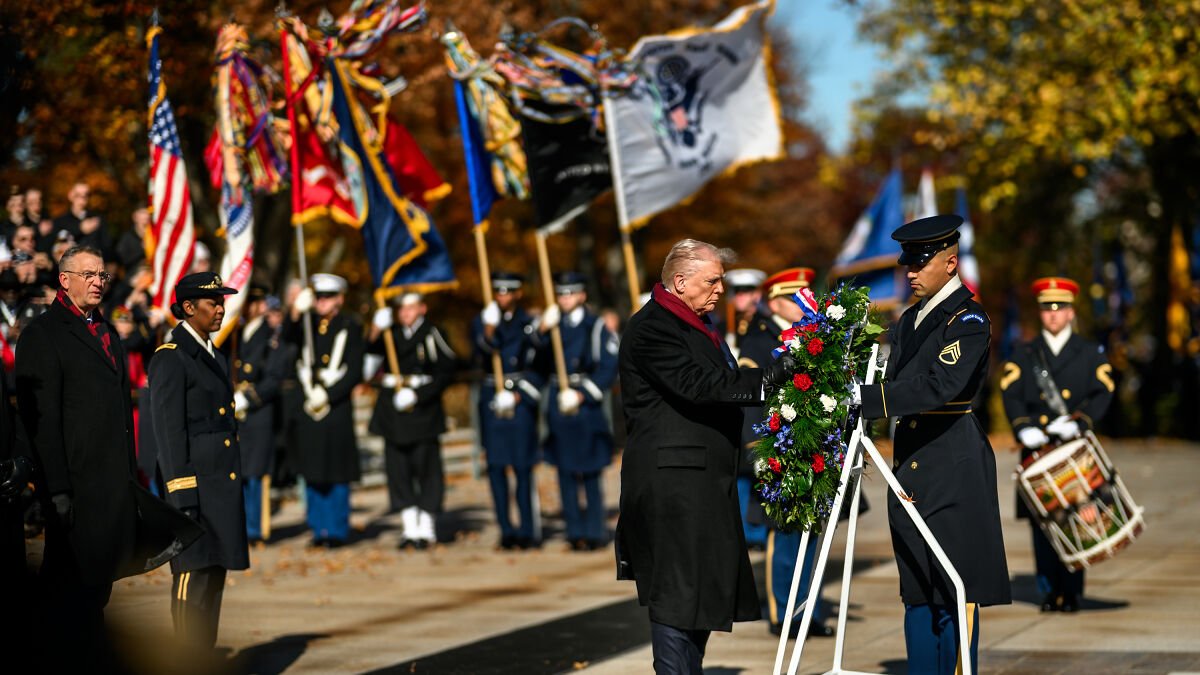 Trump paying tribute to fallen heroes in a Veterans Day wreath-laying ceremony with military honor and flags in background