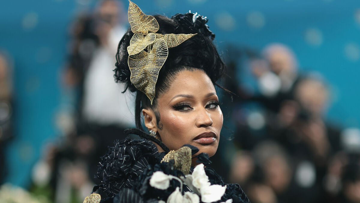 Nicki Minaj wearing elaborate headpiece and gown, facing sideways, related to backlash for teaming up with Trump administration