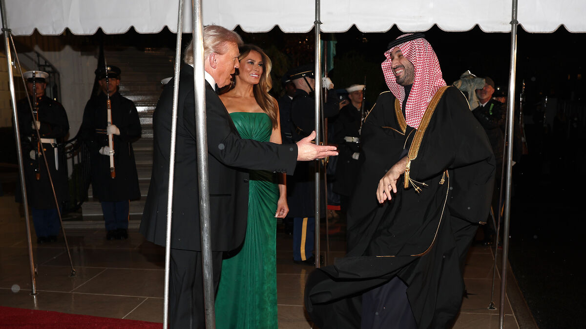 Melania Trump in a green dress making a subtle gesture to Saudi Crown Prince at a White House dinner event.