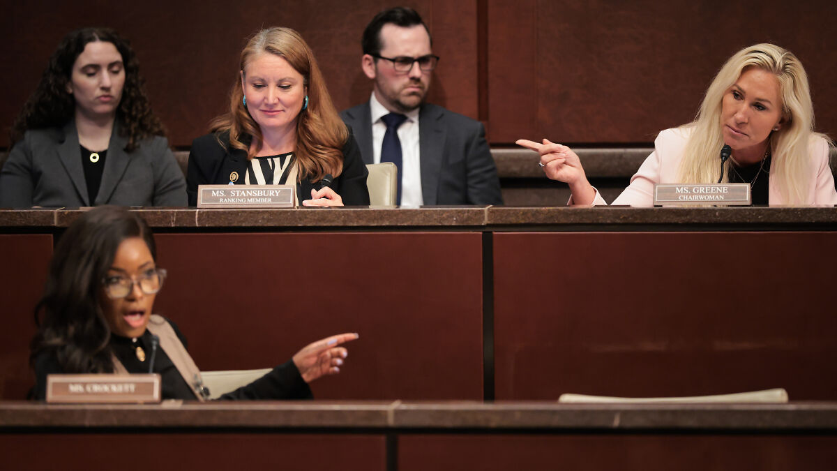 Jasmine Crockett pointing and speaking to Marjorie Taylor Greene during a Congress hearing with attentive members.