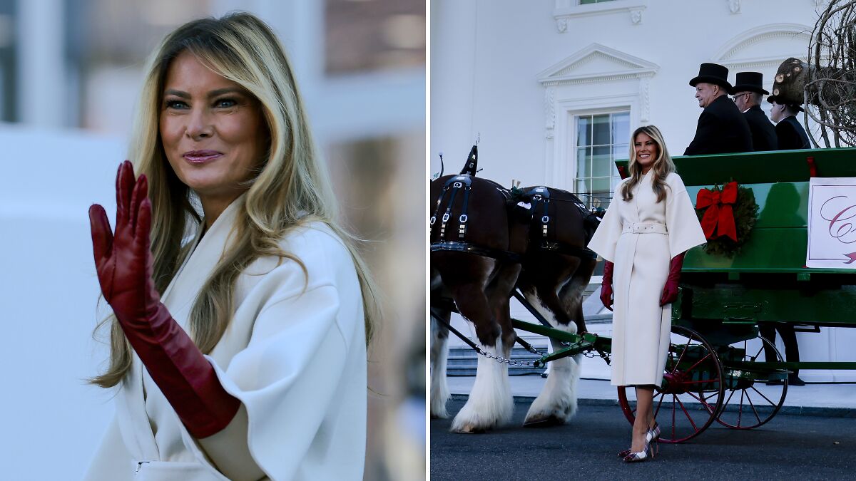 Melania Trump in white coat and red gloves at White House Christmas ceremony beside horse-drawn carriage and attendants.