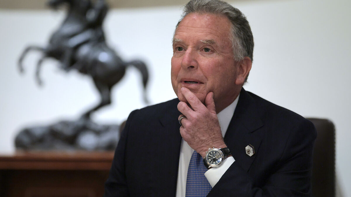 Man in suit and watch sitting thoughtfully with hand on chin, related to Trump man of peace and Ukraine deal keywords.