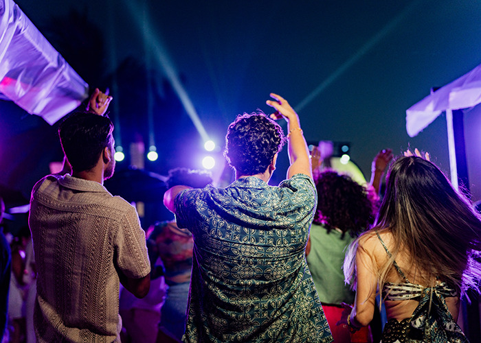 Crowd of young people dancing and enjoying music at night, representing Colombian musicians linked to Coco Chanel substance.