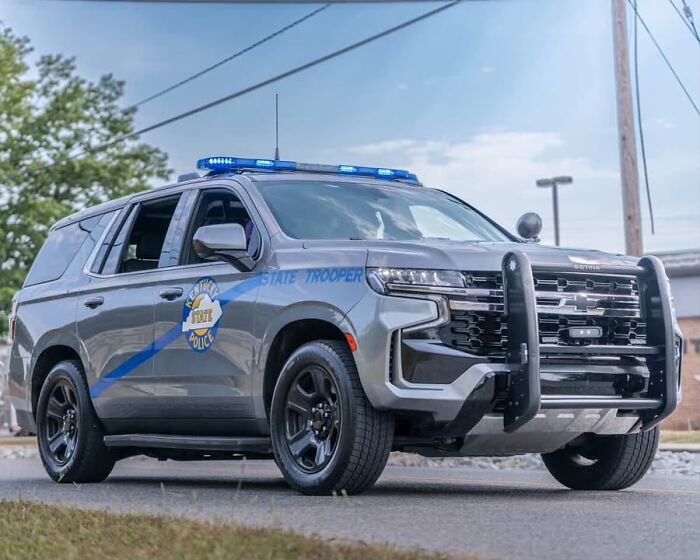 State trooper police SUV with blue lights on, parked on a street near a house fire scene involving children and family injuries. State trooper police SUV with blue lights on, parked on a street near a house fire scene involving children and family injuries.