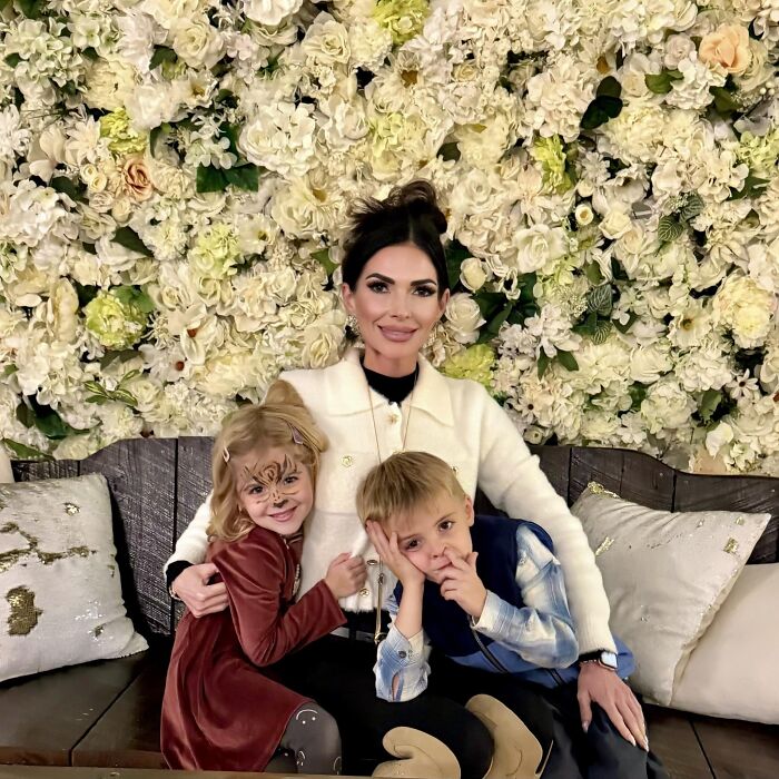 Mom with twin 6-year-olds sitting on a bench, surrounded by floral background, involved in mansion tragedy amid divorce. Mom with twin 6-year-olds sitting on a bench, surrounded by floral background, involved in mansion tragedy amid divorce.