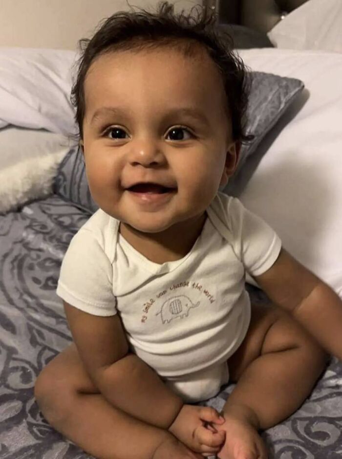 Smiling toddler sitting on bed, related to high-profile college dorm case involving partner’s child and pageant queen. Smiling toddler sitting on bed, related to high-profile college dorm case involving partner’s child and pageant queen.