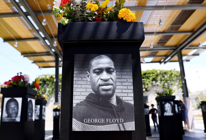 Black and white image of George Floyd displayed on a pedestal with flowers at BLM Plaza amid renaming debate involving Nancy Mace and Charlie Kirk. Black and white image of George Floyd displayed on a pedestal with flowers at BLM Plaza amid renaming debate involving Nancy Mace and Charlie Kirk.