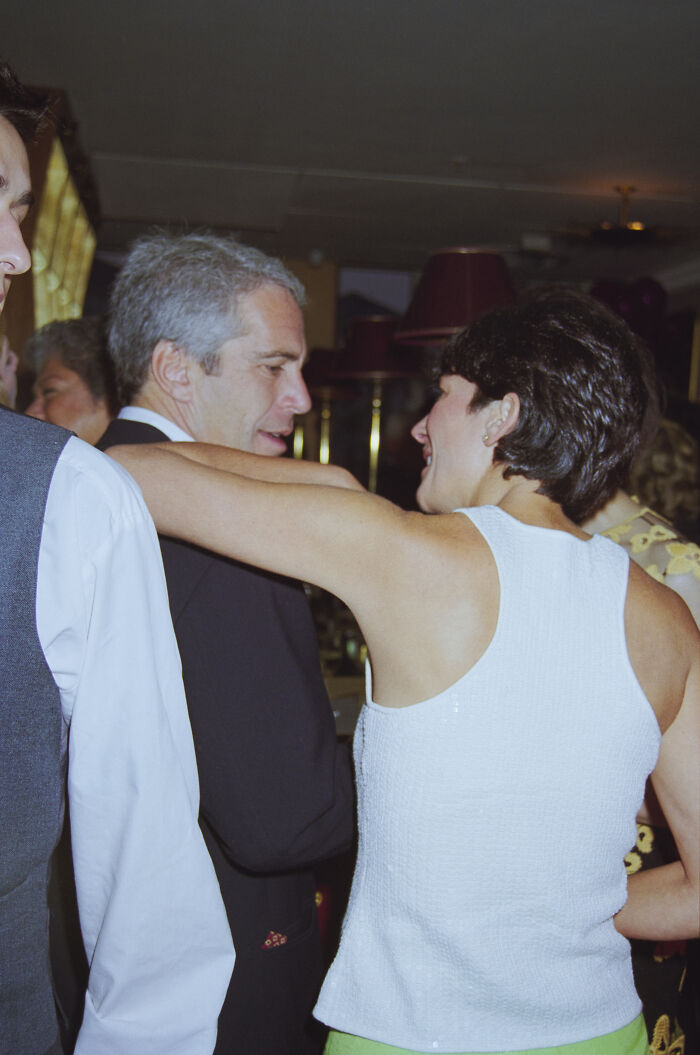 Man with gray hair and woman in white top chatting at a party amid Epstein bank records discussion and island photo controversy.