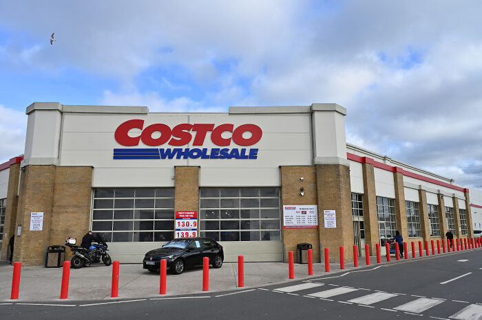Costco Wholesale store exterior with car parked outside under a cloudy sky related to tariffs legal dispute.