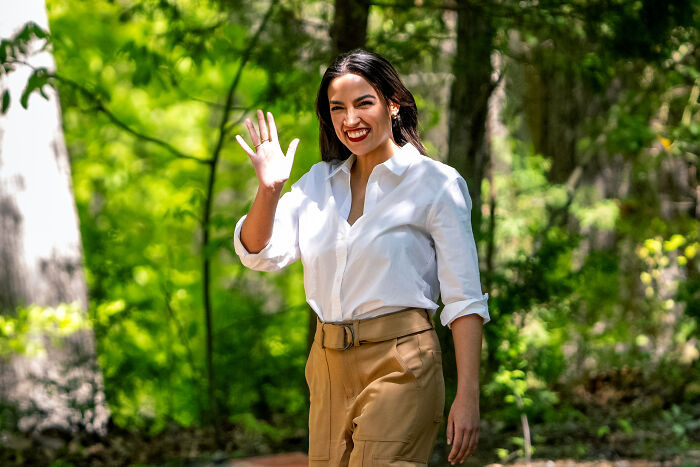AOC smiling and waving outdoors, linked to reports of spending on luxury hotels, fine dining, and Puerto Rico venue expenses. AOC smiling and waving outdoors, linked to reports of spending on luxury hotels, fine dining, and Puerto Rico venue expenses.