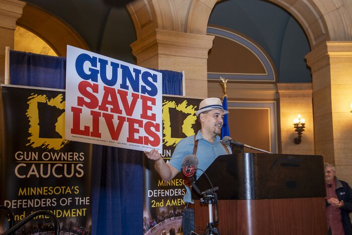 Man holding a guns save lives sign at a podium during a gun owners caucus event on gun laws in the U.S. debate Man holding a guns save lives sign at a podium during a gun owners caucus event on gun laws in the U.S. debate