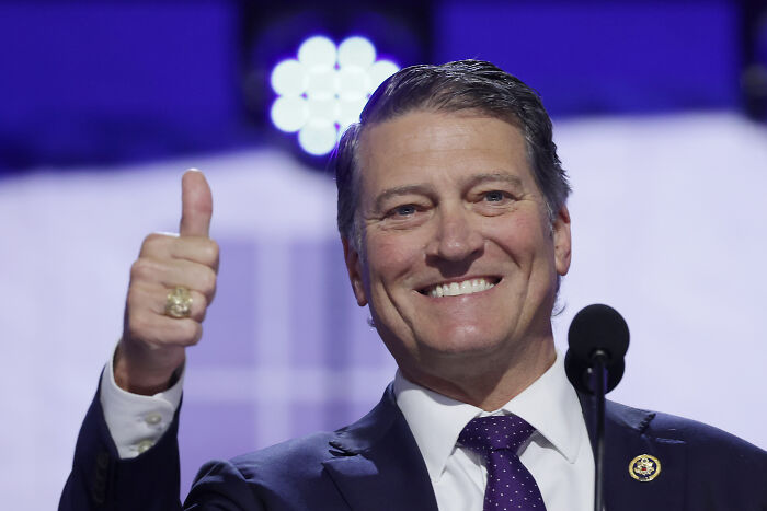 Man in suit giving thumbs up and smiling during a speech, related to Trump White House doctor health comparison. Man in suit giving thumbs up and smiling during a speech, related to Trump White House doctor health comparison.