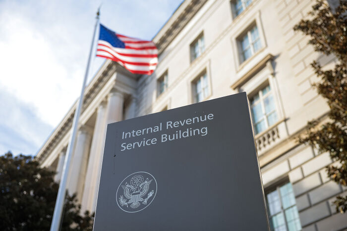 Sign for Internal Revenue Service building outside a government office with an American flag, related to IRS agents and tax on tips. Sign for Internal Revenue Service building outside a government office with an American flag, related to IRS agents and tax on tips.
