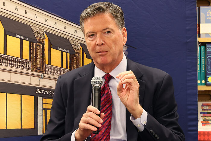 Man in a suit holding a microphone, speaking at an event related to Trump’s chief of staff and alcoholic personality claims. Man in a suit holding a microphone, speaking at an event related to Trump’s chief of staff and alcoholic personality claims.