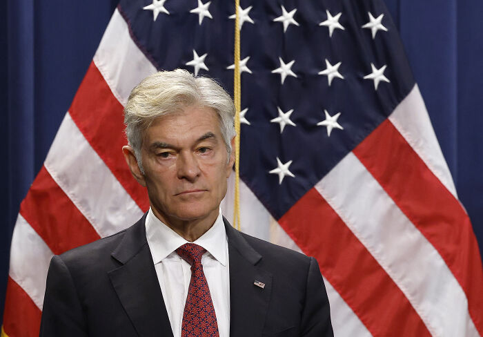 Dr. Oz standing in front of American flags, addressing federal workers after government shutdown during holiday season. Dr. Oz standing in front of American flags, addressing federal workers after government shutdown during holiday season.