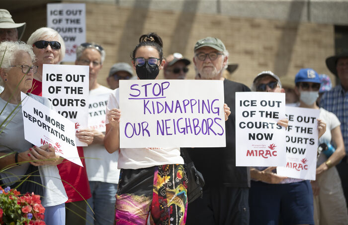 Protesters holding signs demanding ICE out of the courts and stopping deportations during immigration rally.