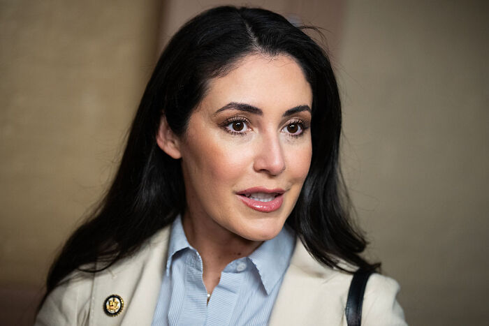 A confident MAGA woman speaking at an event, highlighting the MAGA women revolt against House Speaker Mike Johnson. A confident MAGA woman speaking at an event, highlighting the MAGA women revolt against House Speaker Mike Johnson.