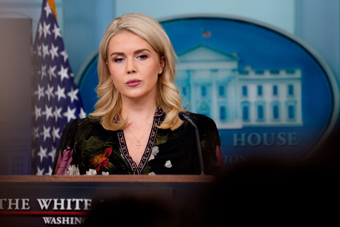 Karoline Leavitt speaking at White House press briefing with American flag and White House emblem in background.