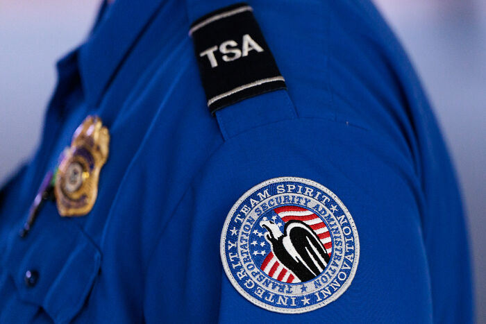 Close-up of TSA staff uniform badge and patch highlighting a hot mic moment with TSA staff feeling terrified at Kristi Noem event. Close-up of TSA staff uniform badge and patch highlighting a hot mic moment with TSA staff feeling terrified at Kristi Noem event.
