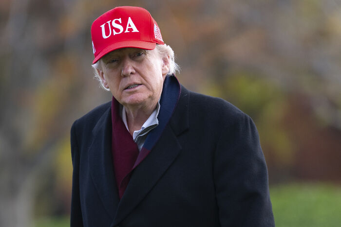 Former President Trump wearing a red USA hat outdoors, related to White House revealing reason behind Trump’s MRI scan.