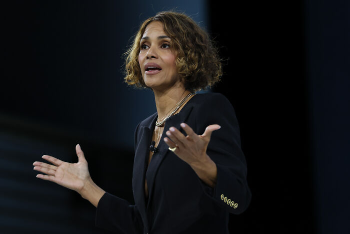 Halle Berry speaking at an event with expressive hand gestures amid Gavin Newsom’s devaluing women discussion.
