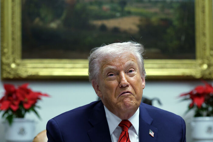 Donald Trump sitting in a suit and red tie in an office setting with plants and a framed painting in the background. Donald Trump sitting in a suit and red tie in an office setting with plants and a framed painting in the background.