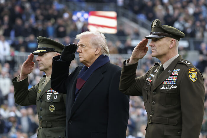 Donald Trump and military officials in uniform saluting during a public event amid war crimes criticism in the Caribbean. Donald Trump and military officials in uniform saluting during a public event amid war crimes criticism in the Caribbean.
