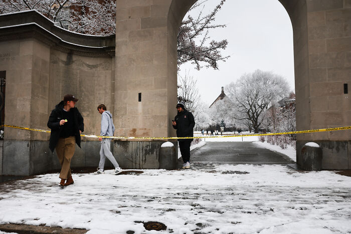 Snow-covered archway cordoned off with yellow tape as people walk nearby, reflecting tightened gun laws debate. Snow-covered archway cordoned off with yellow tape as people walk nearby, reflecting tightened gun laws debate.