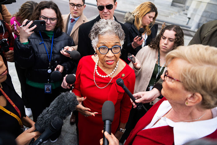 Woman in red dress speaking to reporters amid controversy over musician canceling Kennedy Center show due to Trump rename.