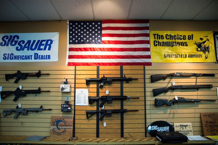 Firearms displayed on a wall under an American flag in a gun store highlighting Australia tightens gun laws debate. Firearms displayed on a wall under an American flag in a gun store highlighting Australia tightens gun laws debate.