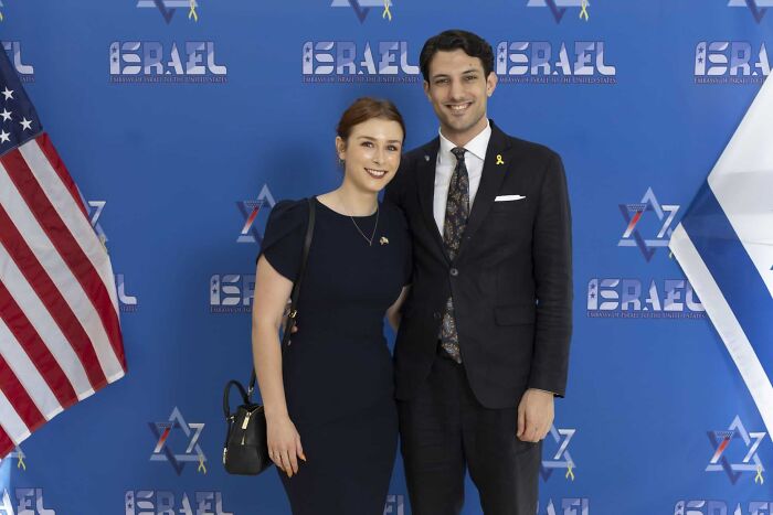 Two people dressed formally standing in front of a blue backdrop with Israel and American flags, highlighting crimes that shocked the nation.