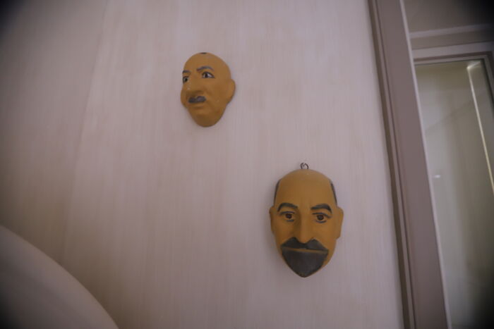 Two carved wooden masks hanging on a wall, evoking a spooky atmosphere linked to island photos and Epstein records.