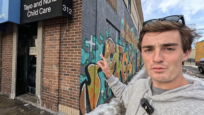 Young man points to a Minnesota child care center with graffiti, highlighting child care funds and fraud concerns. Young man points to a Minnesota child care center with graffiti, highlighting child care funds and fraud concerns.