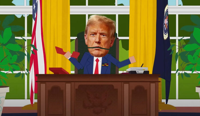 Animated caricature of Trump at a desk with a pen in his mouth, referencing hijacked Kennedy Center website comedy.