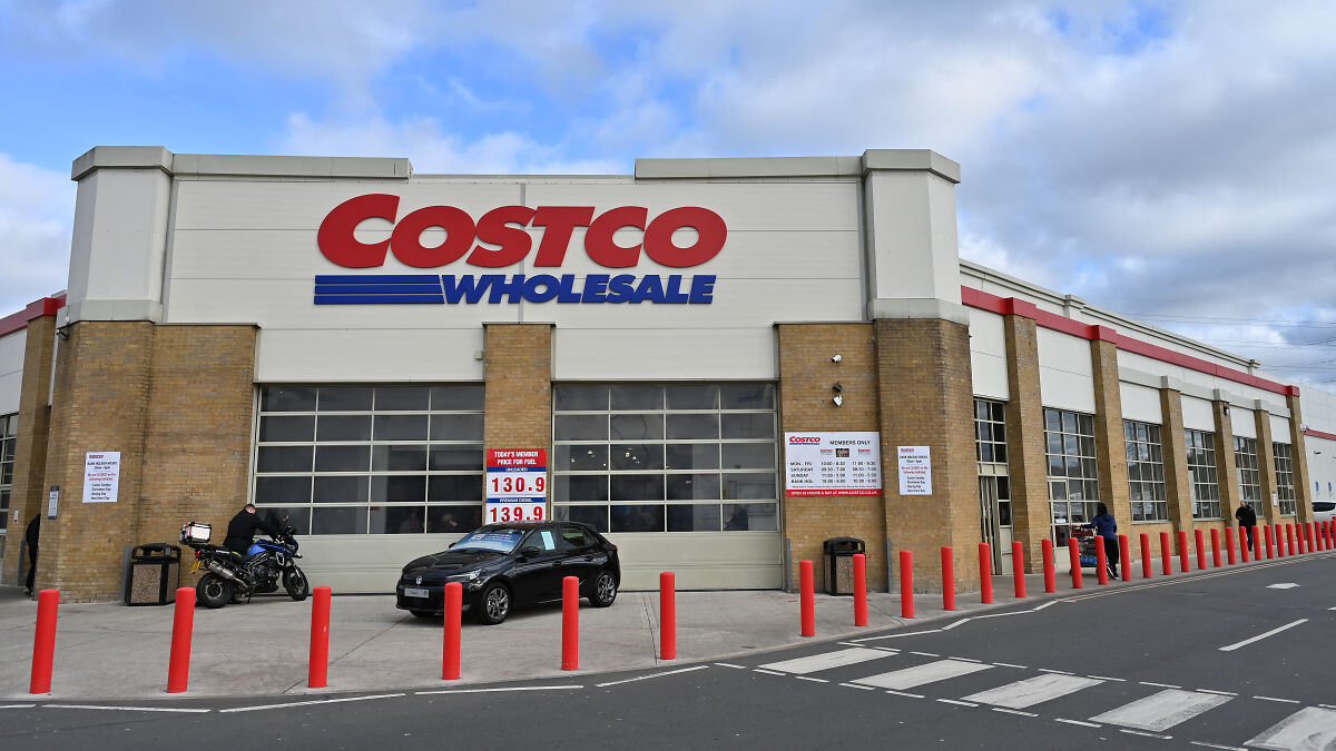 Costco Wholesale store exterior with vehicles parked outside under a cloudy sky, related to tariffs and MAGA response.