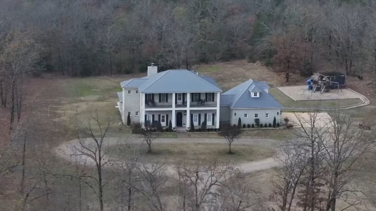 A large mansion surrounded by trees and a playground, related to mom and twin 6-year-olds tragedy.