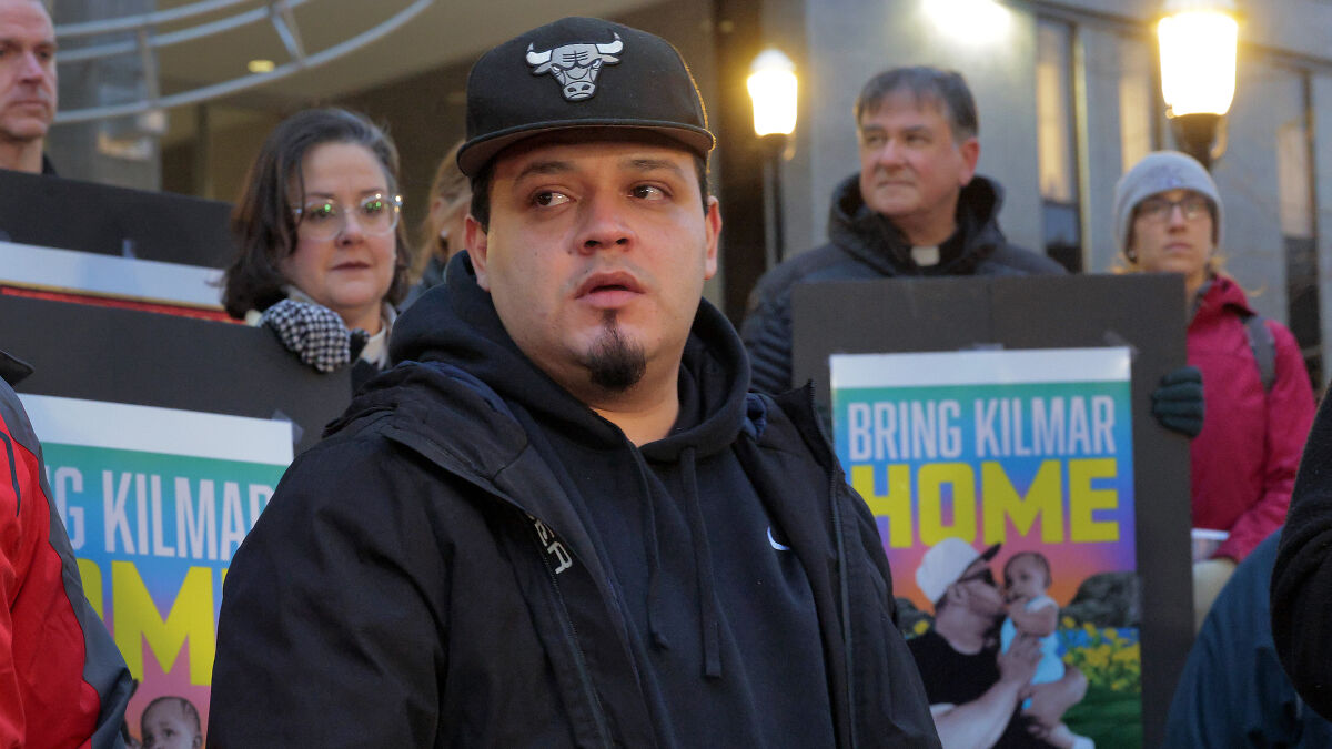 Kilmar Abrego Garcia at a public event with supporters holding Bring Kilmar Home signs during first appearance since release