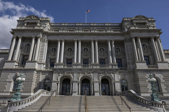 Exterior view of a historic government building with columns under blue sky representing political scandals 2025 context.