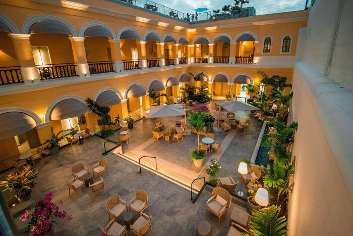 Luxury hotel courtyard in Puerto Rico with fine dining setup and tropical plants under warm lighting at dusk. Luxury hotel courtyard in Puerto Rico with fine dining setup and tropical plants under warm lighting at dusk.