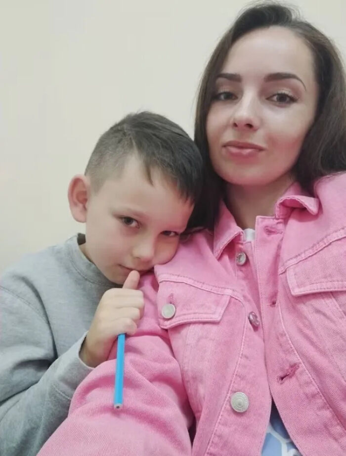 Woman in a pink jacket with a young boy leaning on her, capturing an emotional moment linked to Ukrainian testimony at European Parliament. Woman in a pink jacket with a young boy leaning on her, capturing an emotional moment linked to Ukrainian testimony at European Parliament.