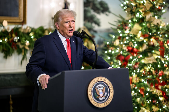 Former president speaking at a podium with presidential seal during a holiday event in a decorated room, Trump Kennedy Center topic. Former president speaking at a podium with presidential seal during a holiday event in a decorated room, Trump Kennedy Center topic.