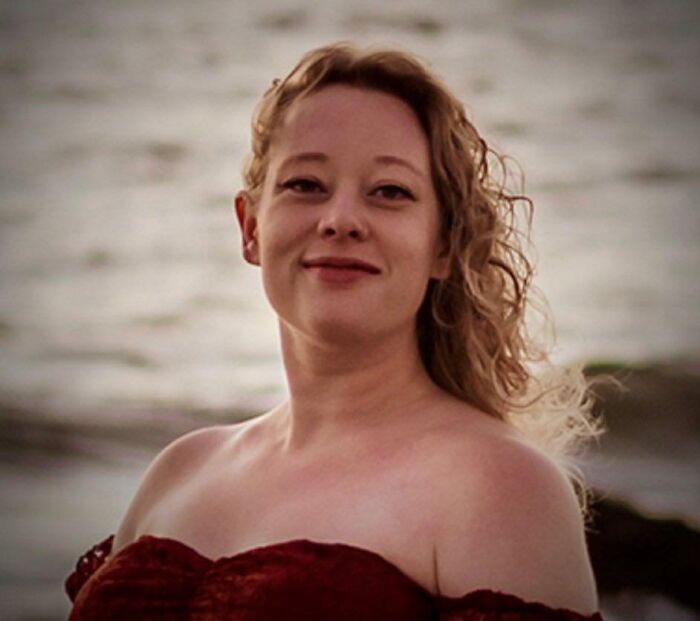 Woman with curly hair wearing a red off-shoulder dress near water, related to Trump cold-blooded insult and fatal ICE shooting. Woman with curly hair wearing a red off-shoulder dress near water, related to Trump cold-blooded insult and fatal ICE shooting.