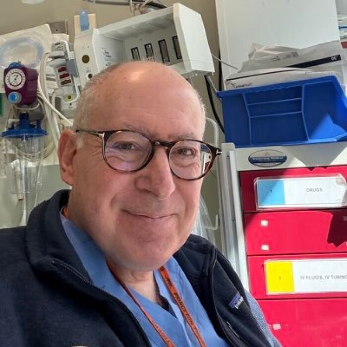 Doctor in hospital setting wearing glasses and blue scrubs revealing hazard in Trump&rsquo;s health admission.