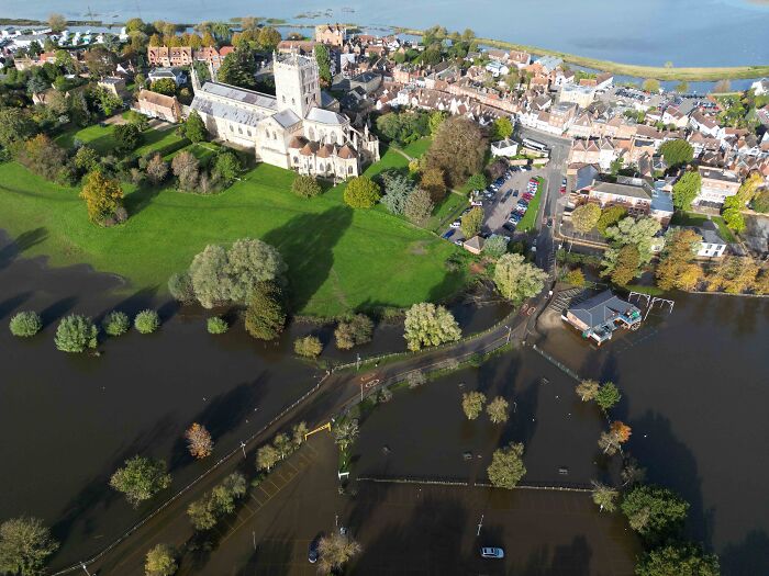 Aerial view of a flooded village with submerged roads and green spaces affected by water overflow after heavy rain. Aerial view of a flooded village with submerged roads and green spaces affected by water overflow after heavy rain.