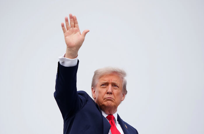Former President Trump raising hand during Davos event urging world leaders to endorse Board of Peace initiatives.
