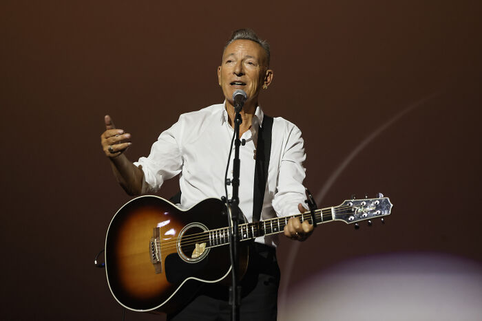 Bruce Springsteen performing live on stage with guitar, dedicating The Promised Land to Renee Good against ICE tactics.