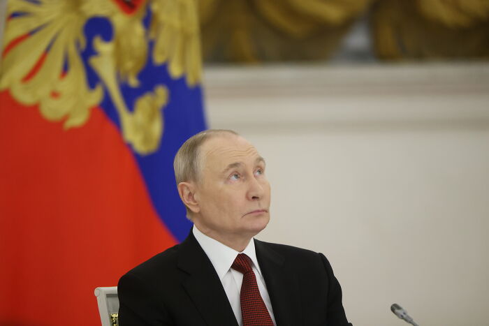 Man in a suit sitting with a red and blue flag behind him, related to Volodymyr Zelenskyy&rsquo;s U.S. Maduro capture topic.